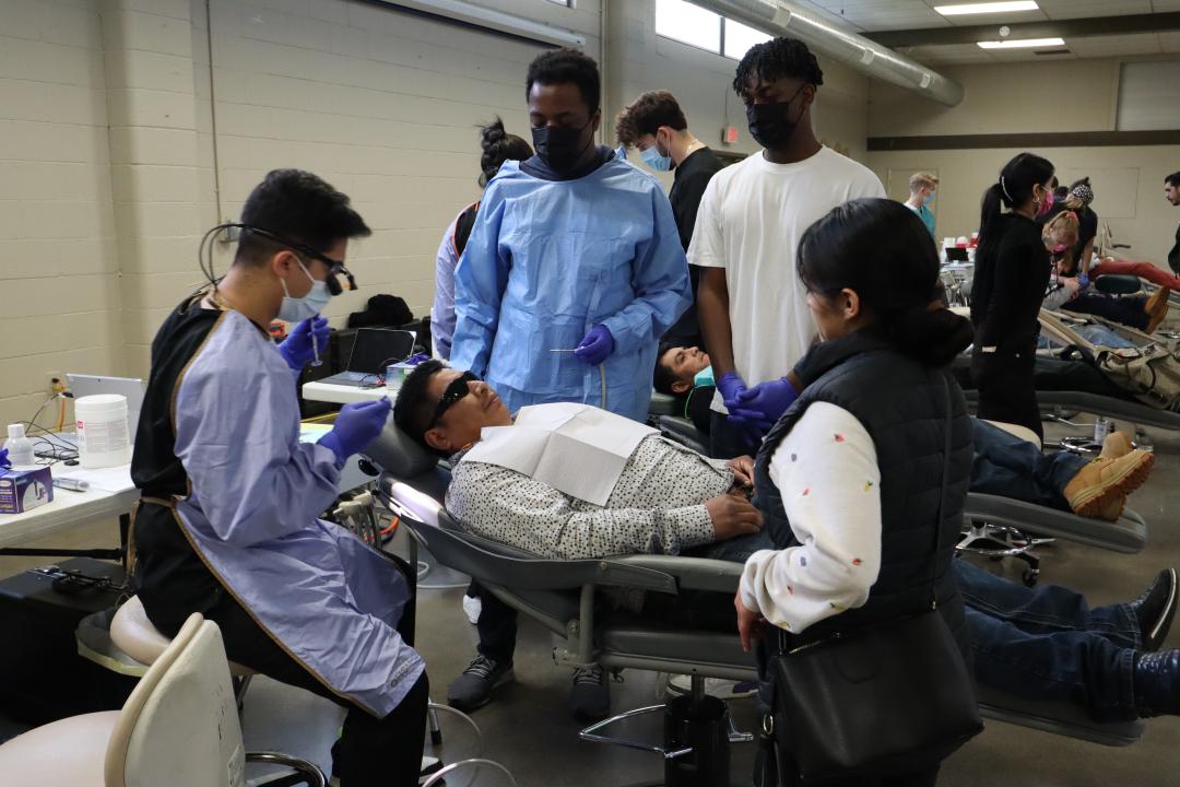 Students help a community member receive dental care.