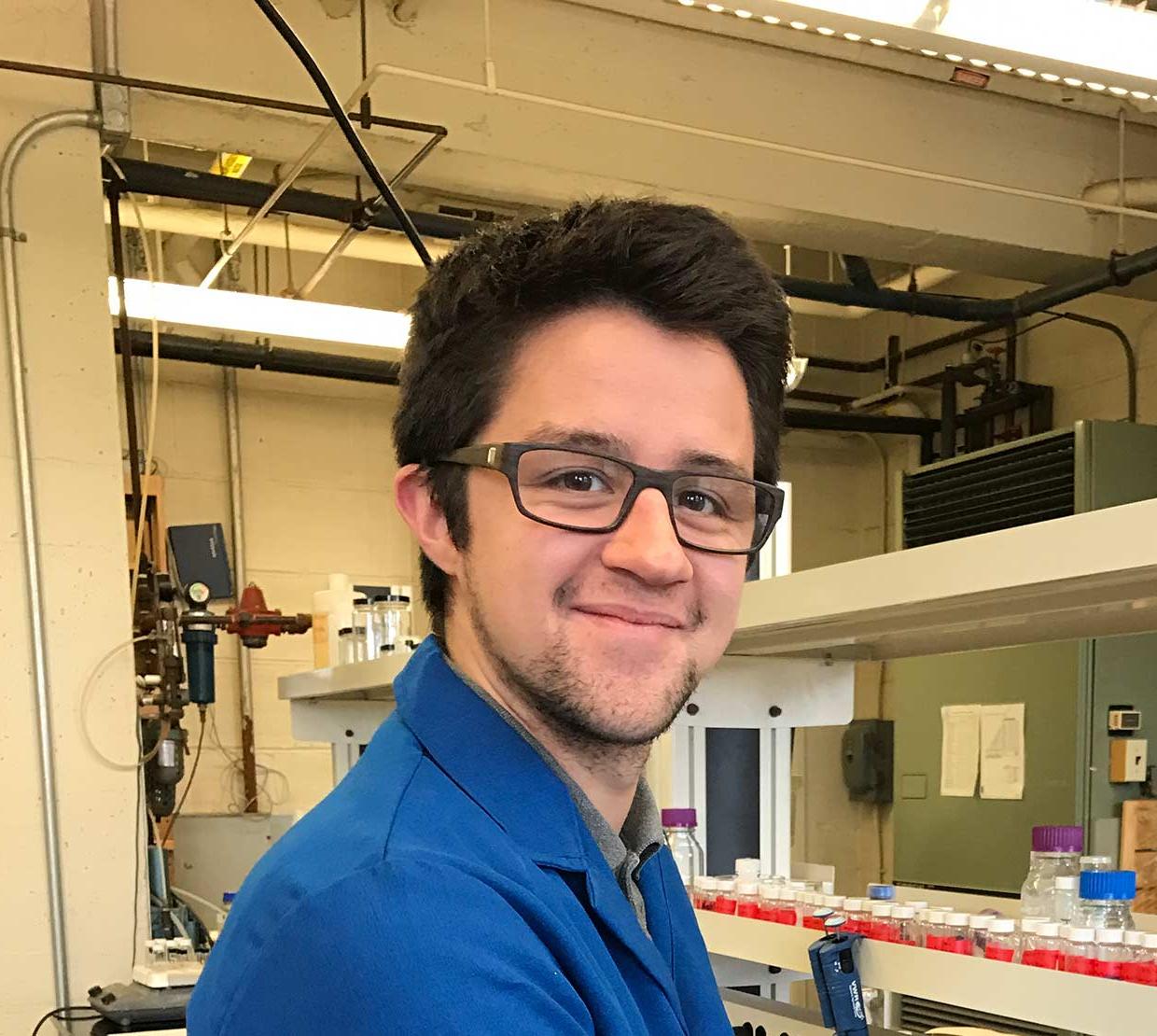 Collin Nicholas Muniz wearing a blue lab coat in chemistry lab