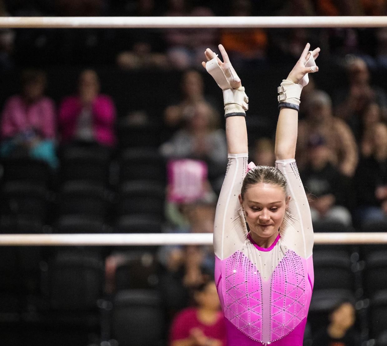 Carley Beeman stands in an OSU leotard after finishing a bar routine.