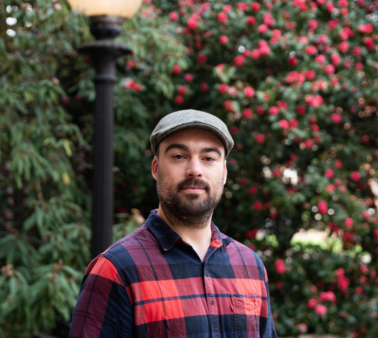 headshot of Tim Zuehlsdorff in flannel and a cap on campus in the spring
