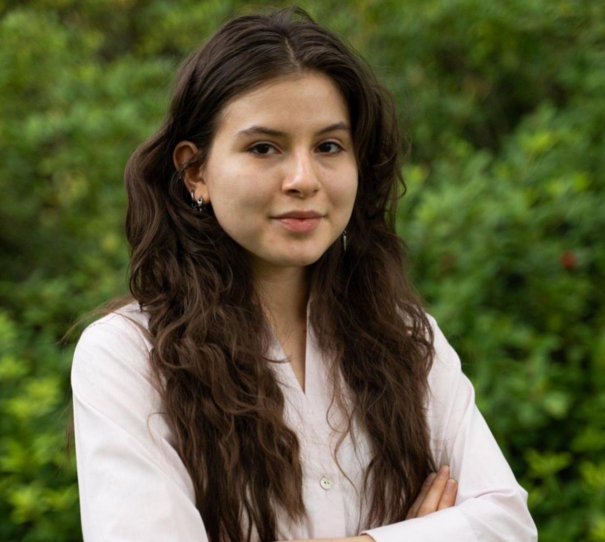 A woman in a pink shirt poses for a headshot.