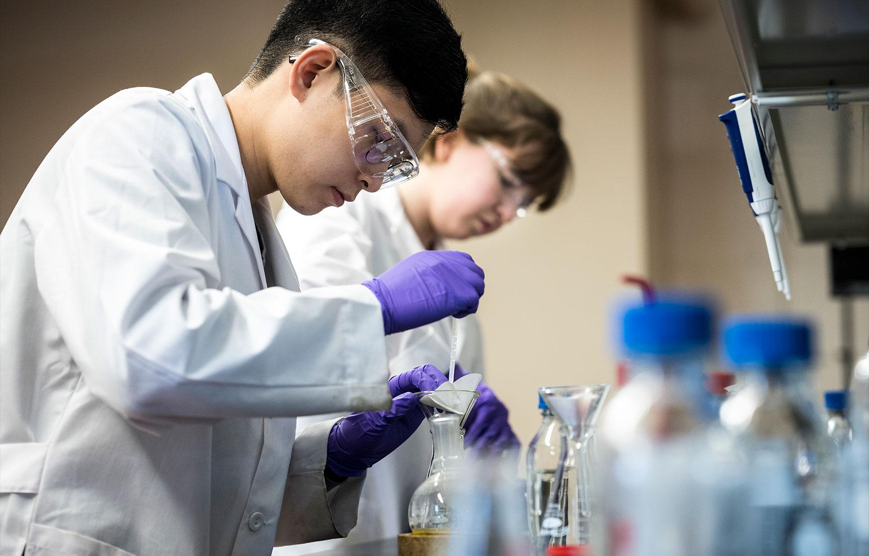 Two students working with chemicals in a lab.