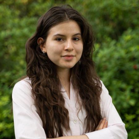 A woman in a pink shirt poses for a headshot.
