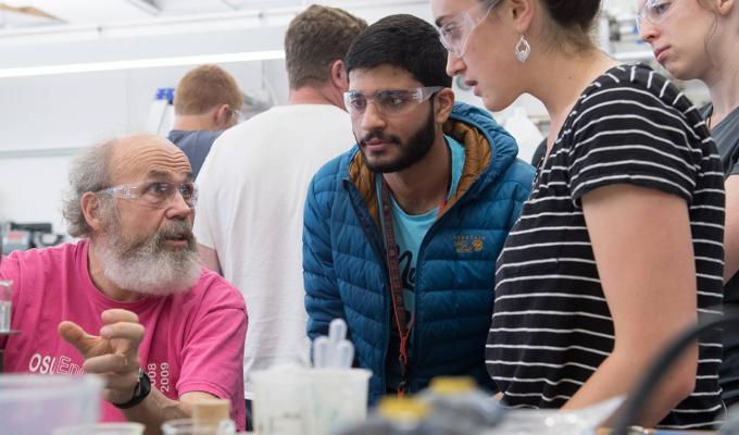 Science students with professor looking at experiment in lab