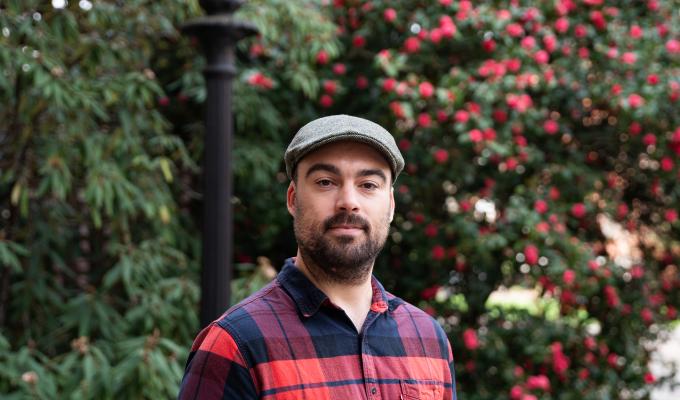 headshot of Tim Zuehlsdorff in flannel and a cap on campus in the spring