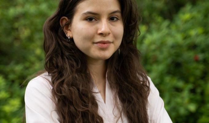 A woman in a pink shirt poses for a headshot.