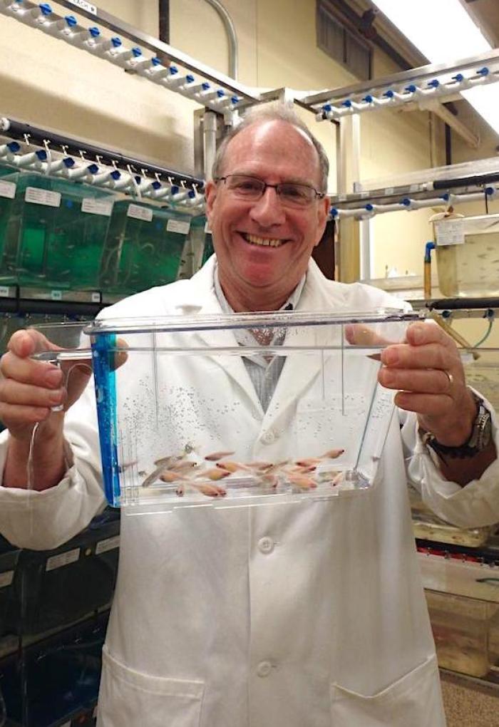 Michael Kent holding up tank of fish in lab