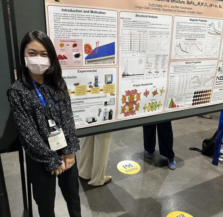 A grad student poses next to their research paper at the 2025 American Chemistry Society national conference.